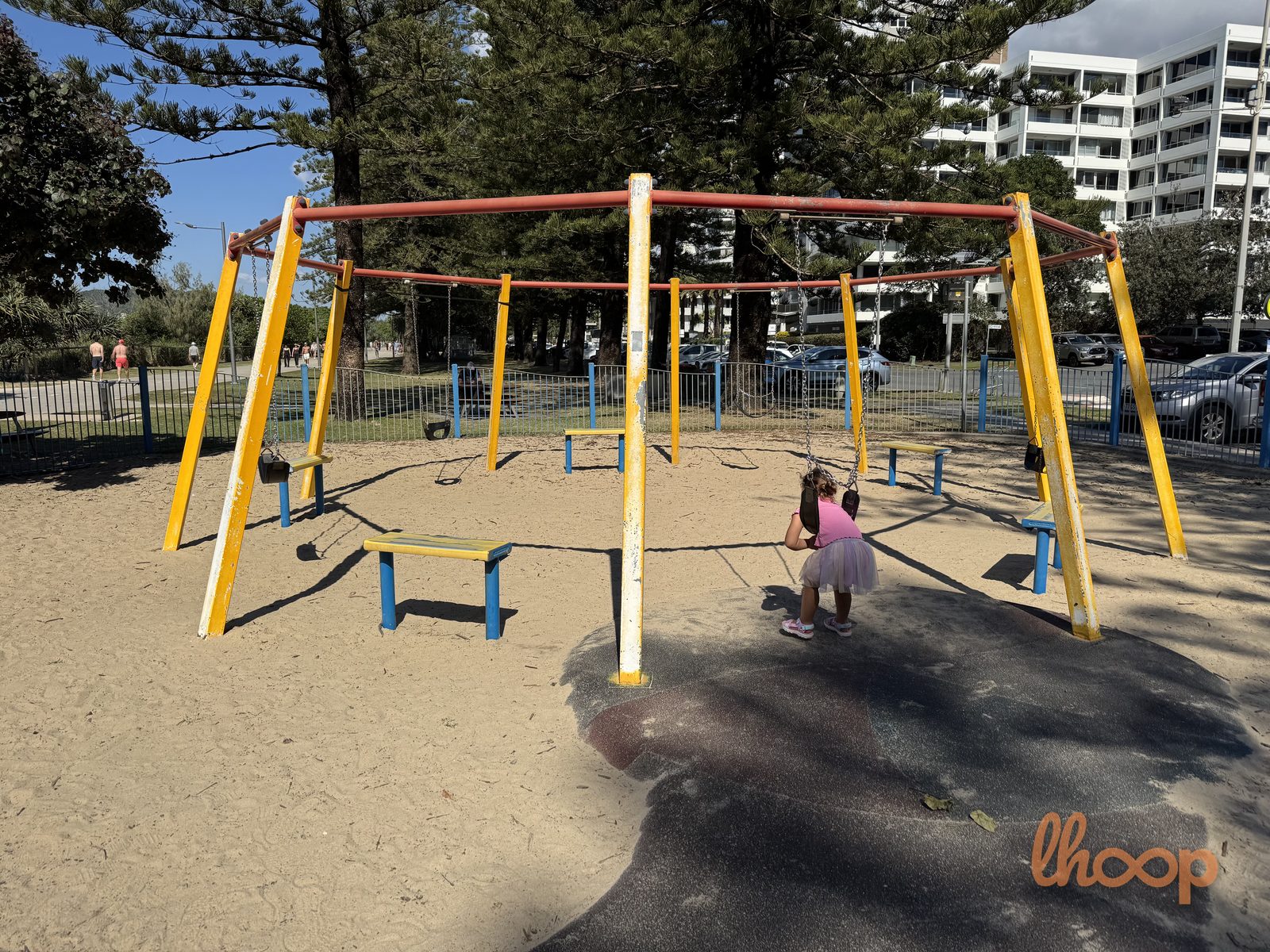 The five-person swing set, a red and yellow round frame with bench seats and swings hanging from it.